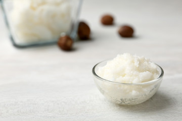 Shea butter in bowl and nuts on table