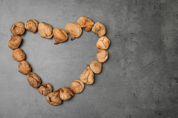 Heart shaped frame made of dried figs on grey background, top view with space for text. Healthy fruit