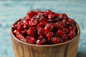 Wooden bowl with cranberries on table, closeup. Dried fruit as healthy snack
