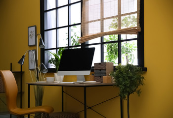Stylish workplace with computer near window at home office. Space for text