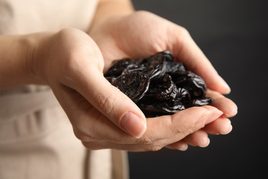 Woman holding handful of dried plums, closeup. Healthy fruit