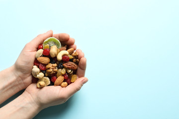 Woman holding handful of different dried fruits and nuts on color background, top view. Space for...