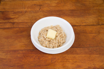 Melting butter on hot oatmeal on rustic wooden background