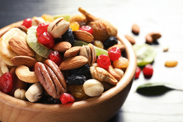 Bowl with different dried fruits and nuts on table, closeup