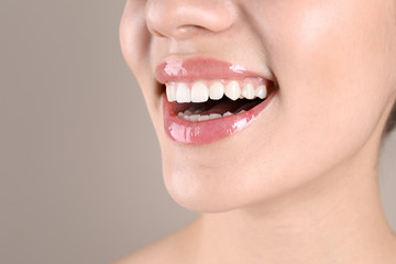 Obraz premium Beautiful young woman with healthy teeth on color background, closeup