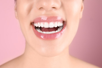 Beautiful young woman with healthy teeth on color background, closeup