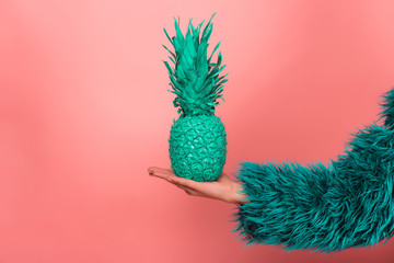 Pop art fashion girl with pineapple turquoise in the hands on a pink background. coat semi fur and...