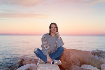 Young woman sitting on rocks at dawn