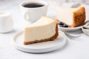 Cheesecake New York with cup of coffee on white table. Closeup view. Coffee break with slice of...