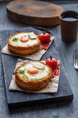 Bread with cheese and yolk for breakfast on black cutting board