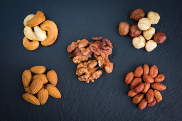 Mix nuts on a black slate background top view. Concept healthy snack.