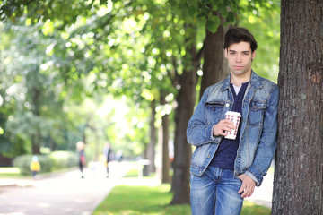 A young man walks in the park at lunch time. A man is on a walk in the city. A student in the park.