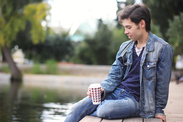 A young man walks in the park at lunch time. A man is on a walk in the city. A student in the park.