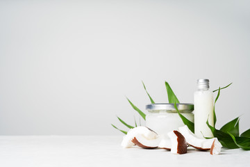 Set with Organic healthy Coconut butter in glass jar with fresh coconut pieces over on coconut leaves on white background with copy space.