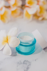 Fototapeta na wymiar skincare moisturiser product on marble table with exotic frangipani flowers