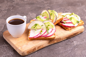 Tasty toasts with radish, avocado and sprouts, cup of coffee