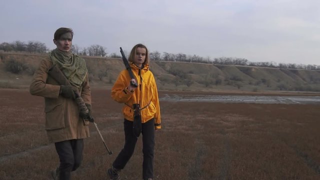 Man and Girl in cloudy wasteland. Stalker - Survival concept. Couple with firearms weapons. Girl with shotgun and Guy with rifle.