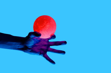Isolated on blue background photo of man holding moon shape illuminated sphere. Surrealistic collage style, contemporary art element for design, posters and banners. Neon purple light. Pop inspiration