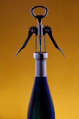 Glass blue bottle with a corkscrew in a dark key on a colored background. A bottle of wine.