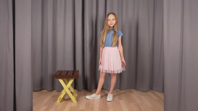 Young model girl posing in studio. Front view, caucasian beautiful teenage model girl posing in different ways in front of camera with a chair aside. Photoposing concept