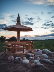 Handmade Wooden Shed Model on the Beach Sands with Stones In Front of it with Dramatic Sunset in Skies Behind it - Concept of Harmony and Peace with a Space for Text