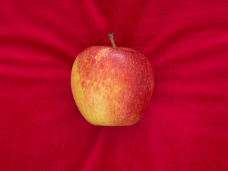 Apple on red velvet cushion, temptation or luxury, with copyspace.