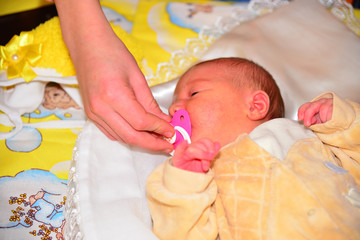 Mom gives newborn baby a pacifier