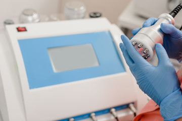 Fototapeta na wymiar Closeup of cosmetologist's hand pressing button on modern laser machine