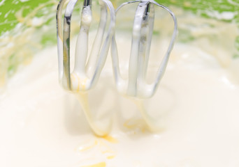 Mixing white egg cream in a bowl with a motor mixer, baking cake