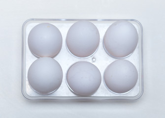 six chicken eggs in a plastic tray from the fridge