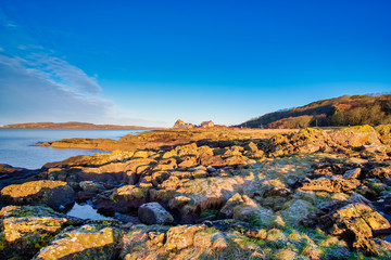 Looking Over to Portencross & Little Cumbrae From Seamill Bay on a Bright but Cold January Day with the Cold Morning Sun Reflecting on the Rocky Lichens Covered Shoreline