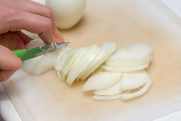 Girl's hand with a knife cutting onions on wooden Board