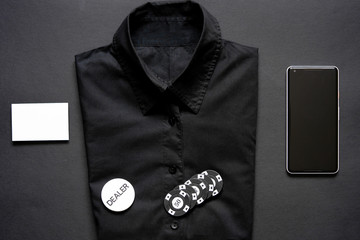 Casino chips, formal shirt, business card and mobile phone on black background.