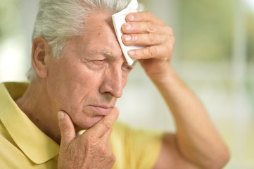 Sad senior man  with headache at home