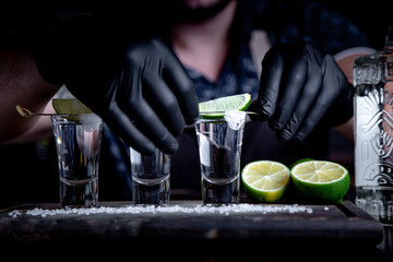 Bartender in decorates tequila lime shots. Mexican, alcohol in shot glasses