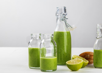 Fresh made healthy green smoothie served in bottles on white background. Fruits and vegetables and seeds ingredients around. Close with copy space. Lifestyle.