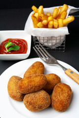Ham and chicken croquettes with fried tomate, chips on dark background
