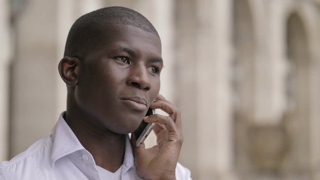 serene young african american man talking by phone in the city