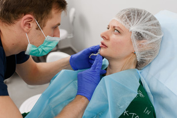 girl do plastic operation in medical clinic; doctor does lip augmentation surgery; injecting...