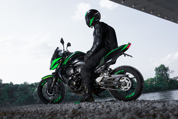 Motorcyclist stop under the bridge over the road waiting for rain to stop