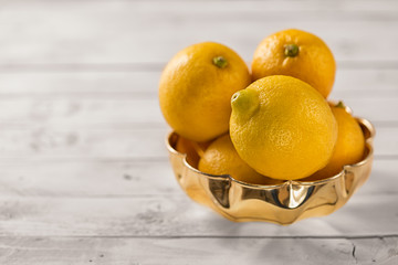 Lemon fruits in a wood bowl on a white rustic wooden table