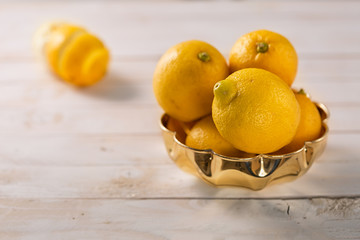 Lemon fruits in a wood bowl on a white rustic wooden table