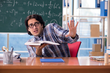 Young funny math teacher in front of chalkboard 