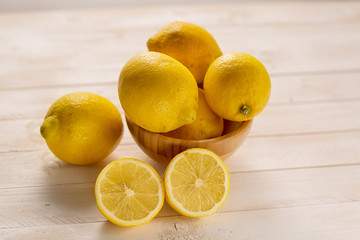 Lemon fruits in a wood bowl on a white rustic wooden table
