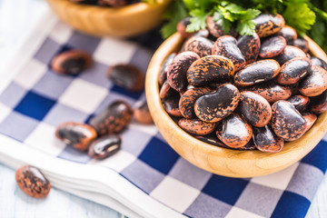 Uncooked beans in wooden bowles  with parsley herbs on kitchen table