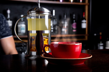 Sea buckthorn tea in french press on a bar background at coffee shop.