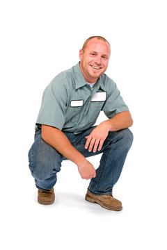 An adult male serviceman employee worker with blank name tag on shirt is squatting and smiling.