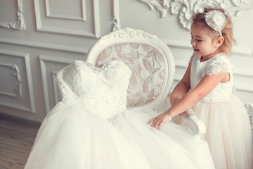 Little fashion cute caucasian kid model in wedding elegant dress posing in classical studio...