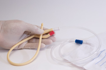 doctor's hands in medical gloves hold a medical catheter, a droplet and urinal