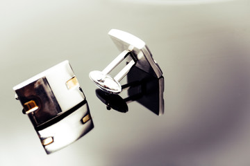 Men's white cufflinks on a gray isolated background.